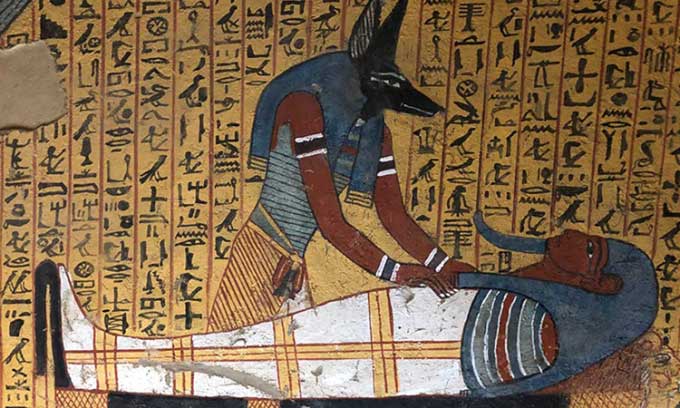 A carving depicting the god Anubis caring for a mummy.