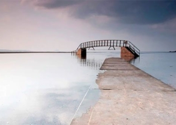 the bridge swaying in the water with a path leading down to the sea 122162
