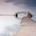 the bridge swaying in the water with a path leading down to the sea 122162