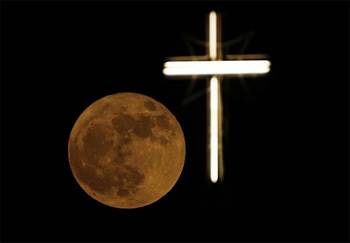 The full moon shining on the cross of St. Joseph's Church in Baghdad (Iraq).