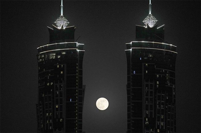 The full moon rises between two towers in Dubai, United Arab Emirates (UAE)
