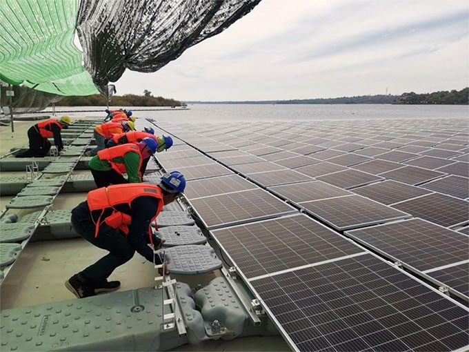 Construction workers check the installation of solar panels at the project.