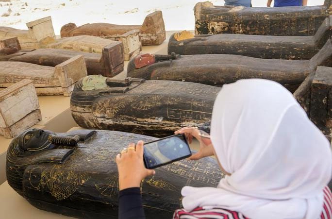 A woman captures images of the mummified remains in the coffins.