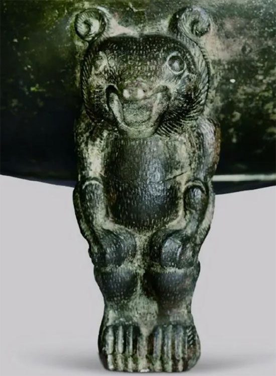 The three legs of the bronze cauldron carved in the shape of bears squatting and grinning.