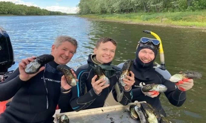 The research team poses with the long-lived mussel population on the St. Croix River.