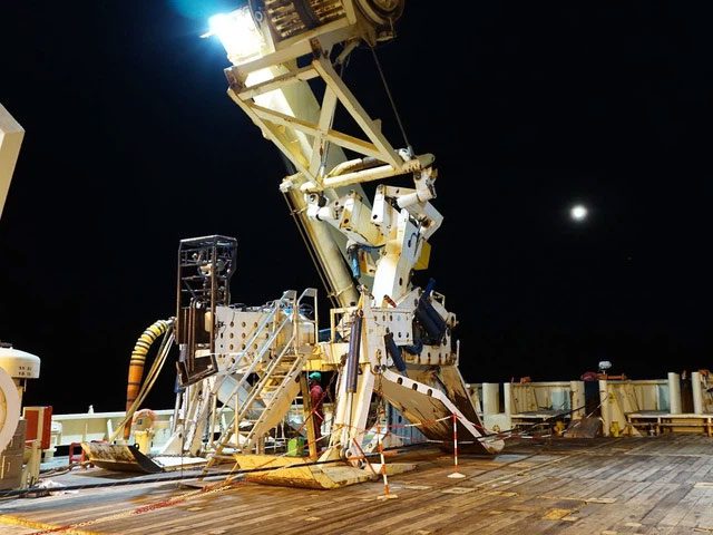 The ship departs the port, laying down the cable spool behind.