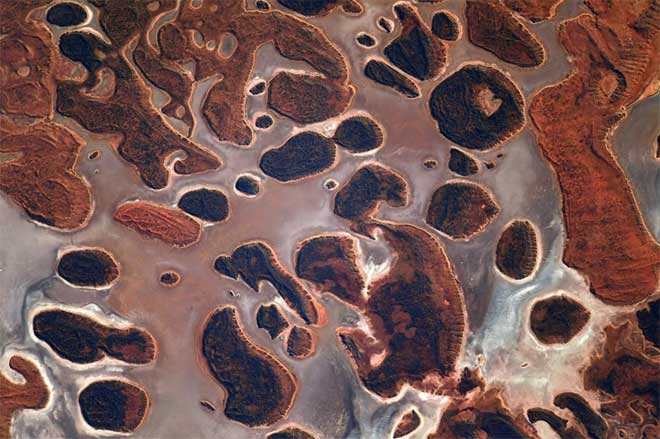 A salt lake in Australia with reddish-brown land masses in the white water.